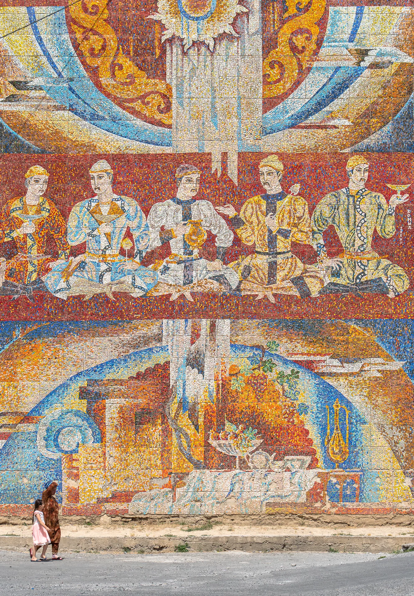 Groot Sovjet-mozaiek op een muur in Panjakent met figuren, druiven en een zon