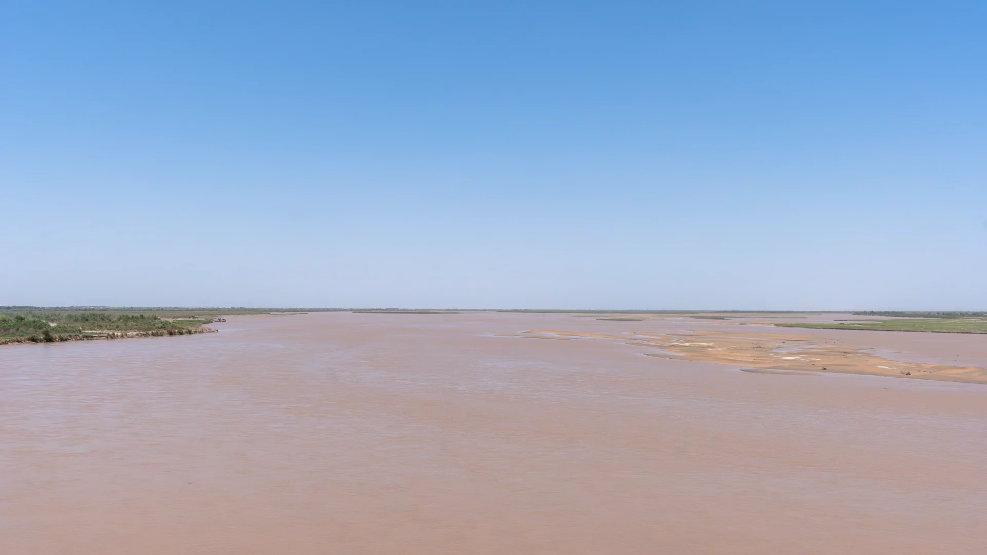 De brede, bruine Amu Darya bij Farap, vlak voor de grens tussen Turkmenistan en Oezbekistan