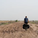 Bepakte reisfiets op een omgewoeld zandspoor in de lege vlakte bij Sarakhs, Turkmenistan