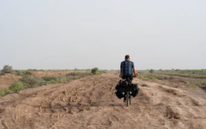 Bepakte reisfiets op een omgewoeld zandspoor in de lege vlakte bij Sarakhs, Turkmenistan