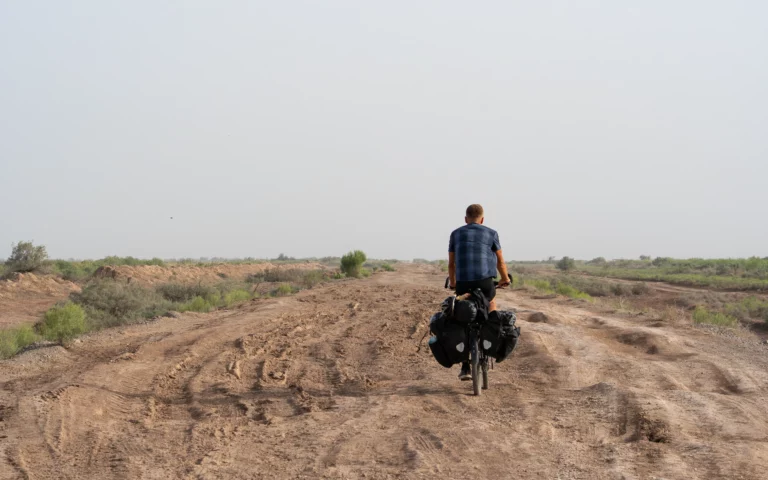 Bepakte reisfiets op een omgewoeld zandspoor in de lege vlakte bij Sarakhs, Turkmenistan