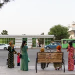 Vrouwen in lange geborduurde koynek langs de weg in de marmerstad Mary, Turkmenistan