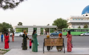 Vrouwen in lange geborduurde koynek langs de weg in de marmerstad Mary, Turkmenistan