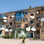 Grauwe flat in Turkmenabat met tientallen schotelantennes aan de gevel