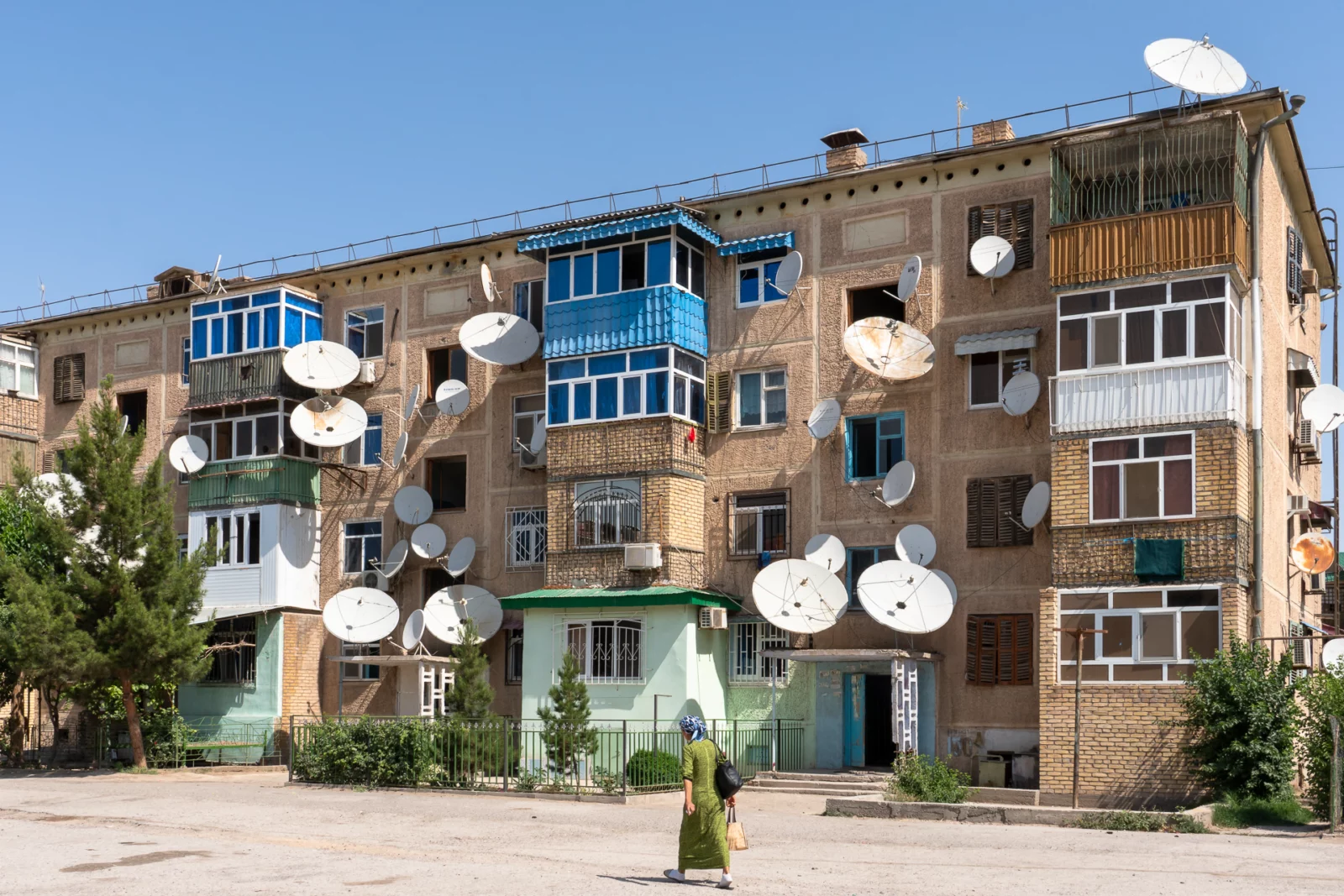 Grauwe flat in Turkmenabat met tientallen schotelantennes aan de gevel