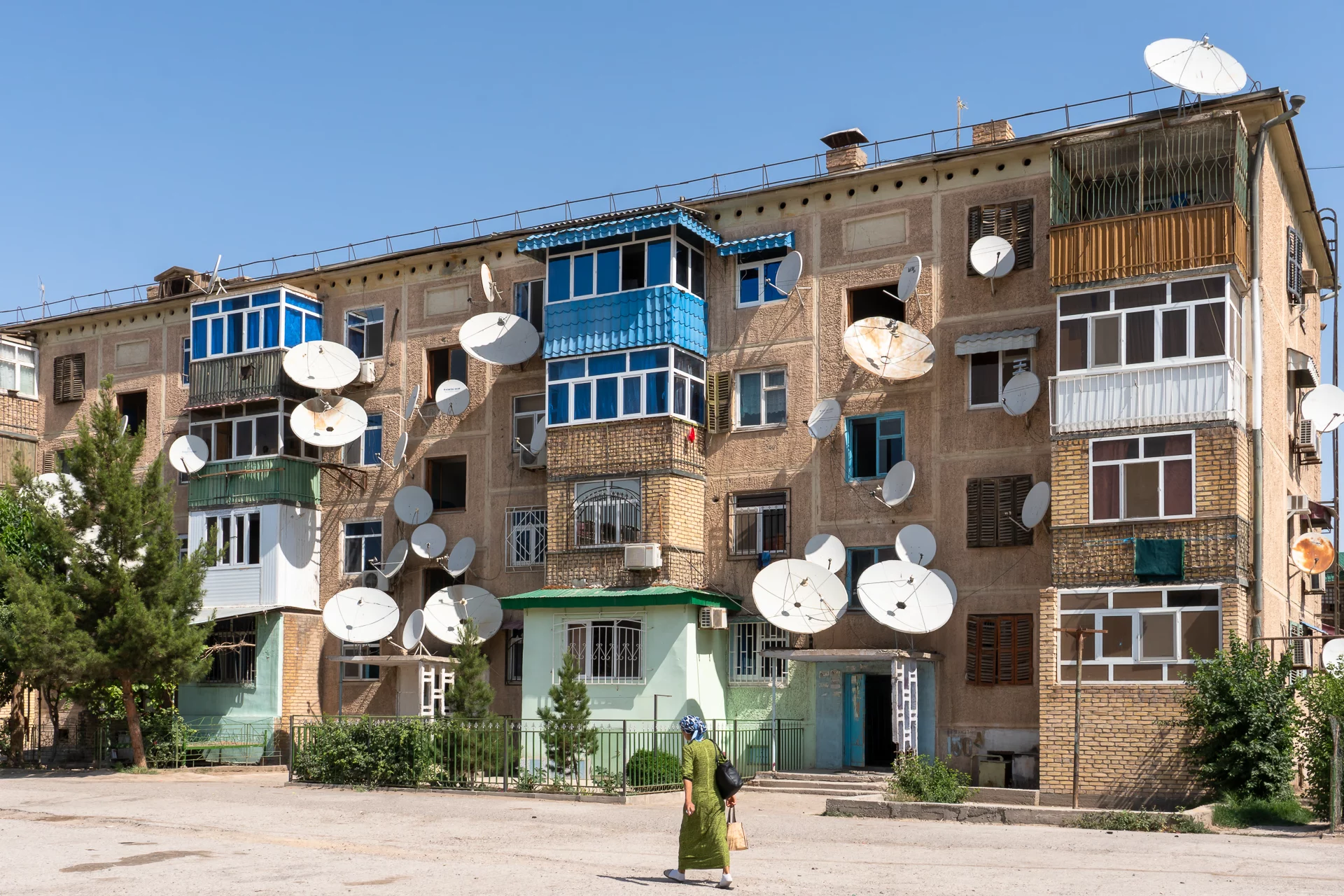 Grauwe flat in Turkmenabat met tientallen schotelantennes aan de gevel