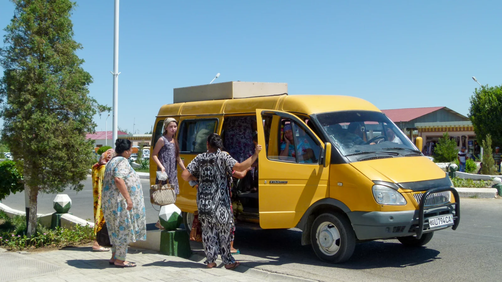 Geel minibusje langs de weg in Oezbekistan, met wachtende passagiers ernaast