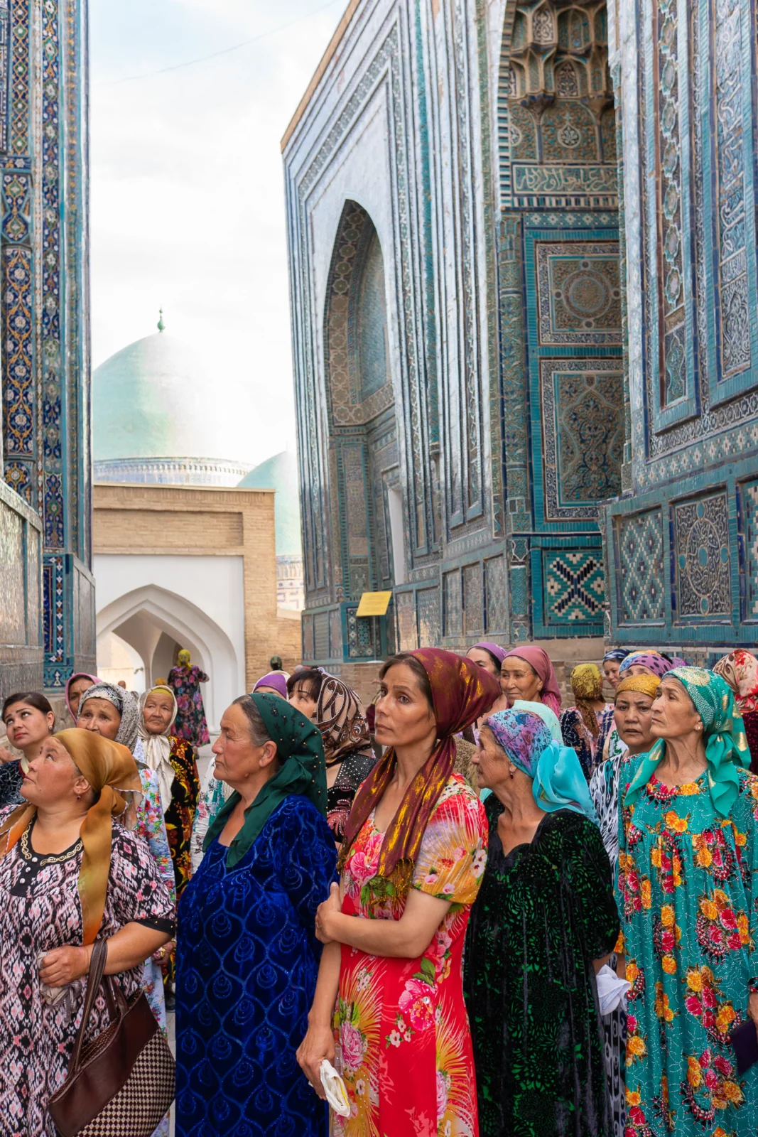 Bezoeksters kijken omhoog naar het tegelwerk in de laan van Shah-i-Zinda in Samarkand