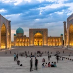 Het uitgelichte Registan-plein in Samarkand tijdens het blauwe uur, met mensen op het plein