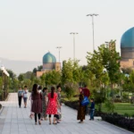 Aangeharkte parkboulevard met lantaarns, een turquoise koepel en de bergen erachter