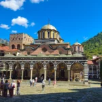 Binnenplaats van het Rilaklooster in Bulgarije, met de zwart-wit gestreepte bogen en de vergulde koepel van de hoofdkerk