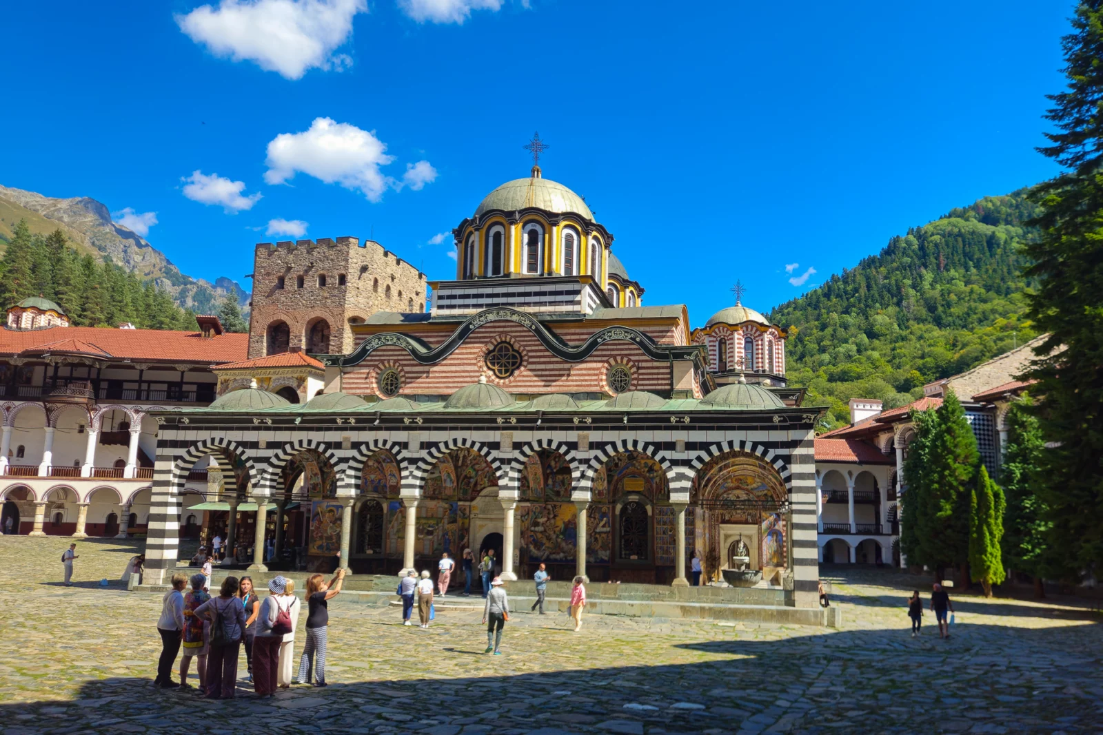 Binnenplaats van het Rilaklooster in Bulgarije, met de zwart-wit gestreepte bogen en de vergulde koepel van de hoofdkerk