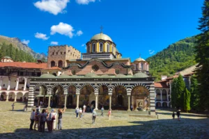 Binnenplaats van het Rilaklooster in Bulgarije, met de zwart-wit gestreepte bogen en de vergulde koepel van de hoofdkerk