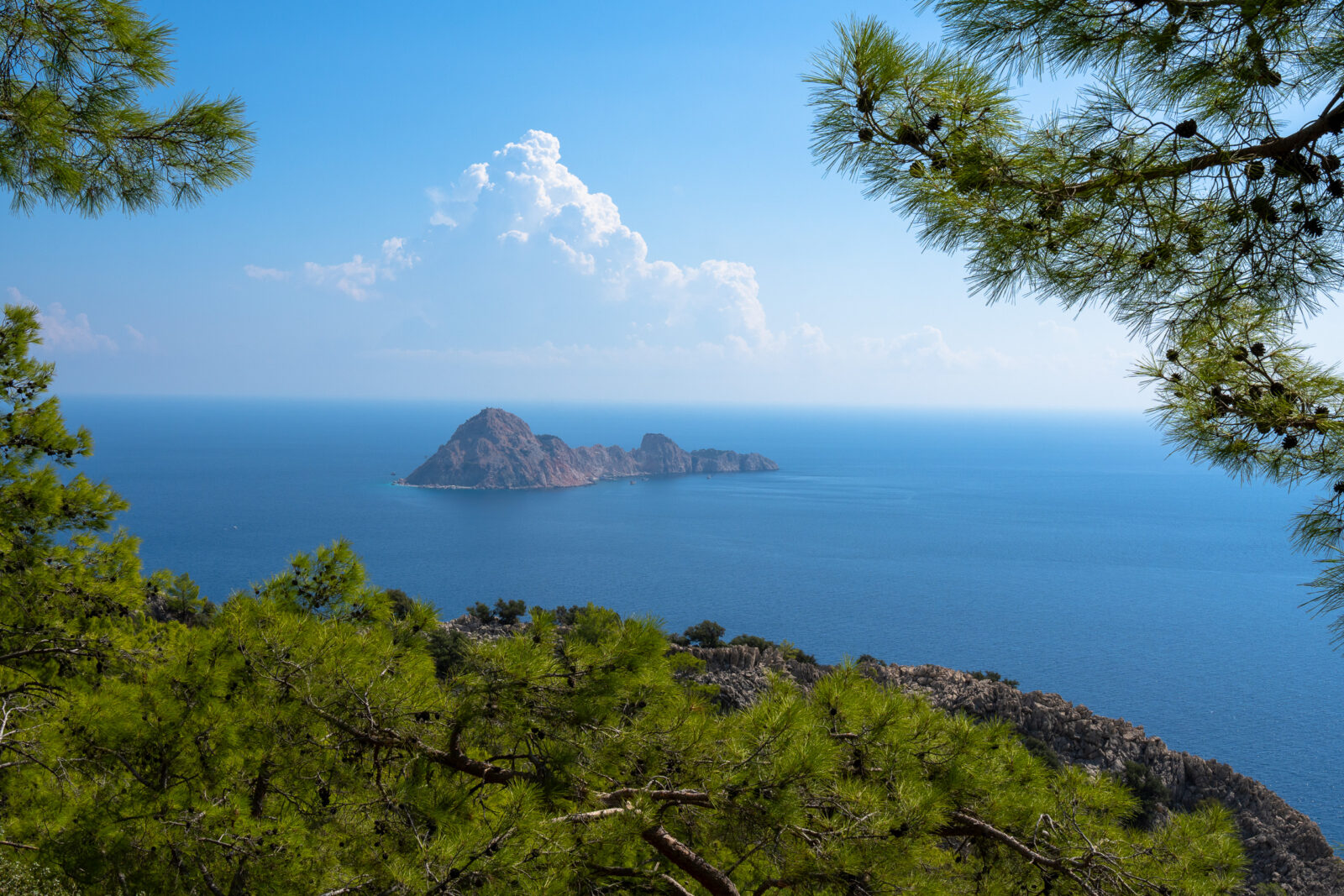 Rotseiland voor de kust van Kaap Gelidonya, gezien tussen dennentakken door vanaf de Lycian Way, Turkije